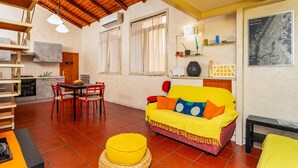 A compact living space with a dining area, a sofa with colorful cushions, a yellow ottoman, and a map on the wall. - Apartment 'La Dimora Di Via Manzoni' with Private Terrace, Wi-Fi and Air Conditioning (Catania)