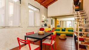 A dining area with a table and chairs, a sofa, and a staircase. - Apartment 'La Dimora Di Via Manzoni' with Private Terrace, Wi-Fi and Air Conditioning (Catania)