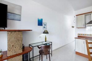 A compact kitchen with a dining area, a TV, and artwork on the walls.