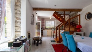 Una cocina amplia con una escalera de madera, una zona de comedor con sillas azules y un tapete rojo.