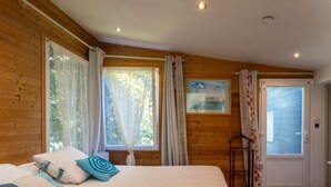 Un dormitorio con cama, cortinas, ventana, puerta y un cuadro.