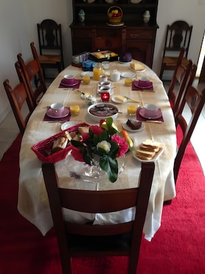 Una mesa de comedor con loza dispuesta para el desayuno, incluyendo pan, huevos y bebidas.