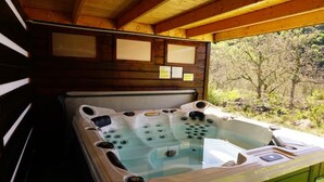 Een hottub in een houten hutje met uitzicht op bomen.