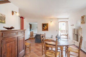 Un coin repas avec une table ronde, des chaises en bois, un buffet, une cheminée et un tableau au mur.