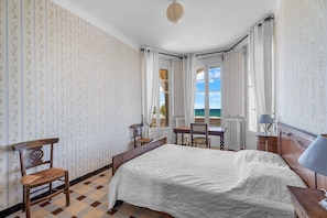 Une chambre à coucher avec un lit, une chaise, un bureau et une vue sur la mer.