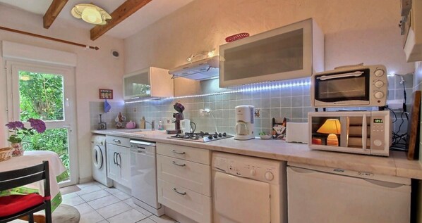 Una cocina con electrodomésticos blancos, estufa a gas, cafetera y microondas.