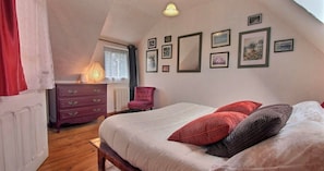 Un dormitorio con cama, cómoda, silla y cuadros en la pared.