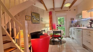 Une cuisine avec un coin repas, un escalier et une vue sur la verdure à l’extérieur.