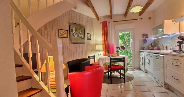 A kitchen with a dining area, a staircase, and a view of greenery outside.