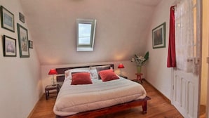 Une chambre à coucher avec un lit, des tables de chevet, une fenêtre et une porte.