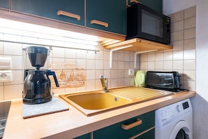 Une cuisine équipée d’une machine à café, d’un grille-pain et d’un lave-linge.