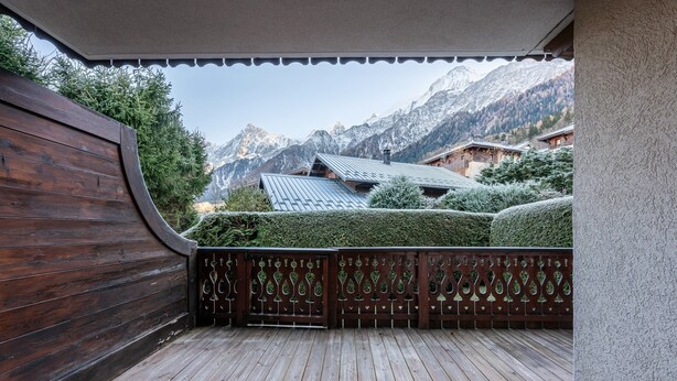 Eine Holzterrasse mit Blick auf Berge und traditionelle Gebäude.
