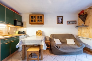 Een kleine keuken met een eettafel, een magnetron en een houten kastje.