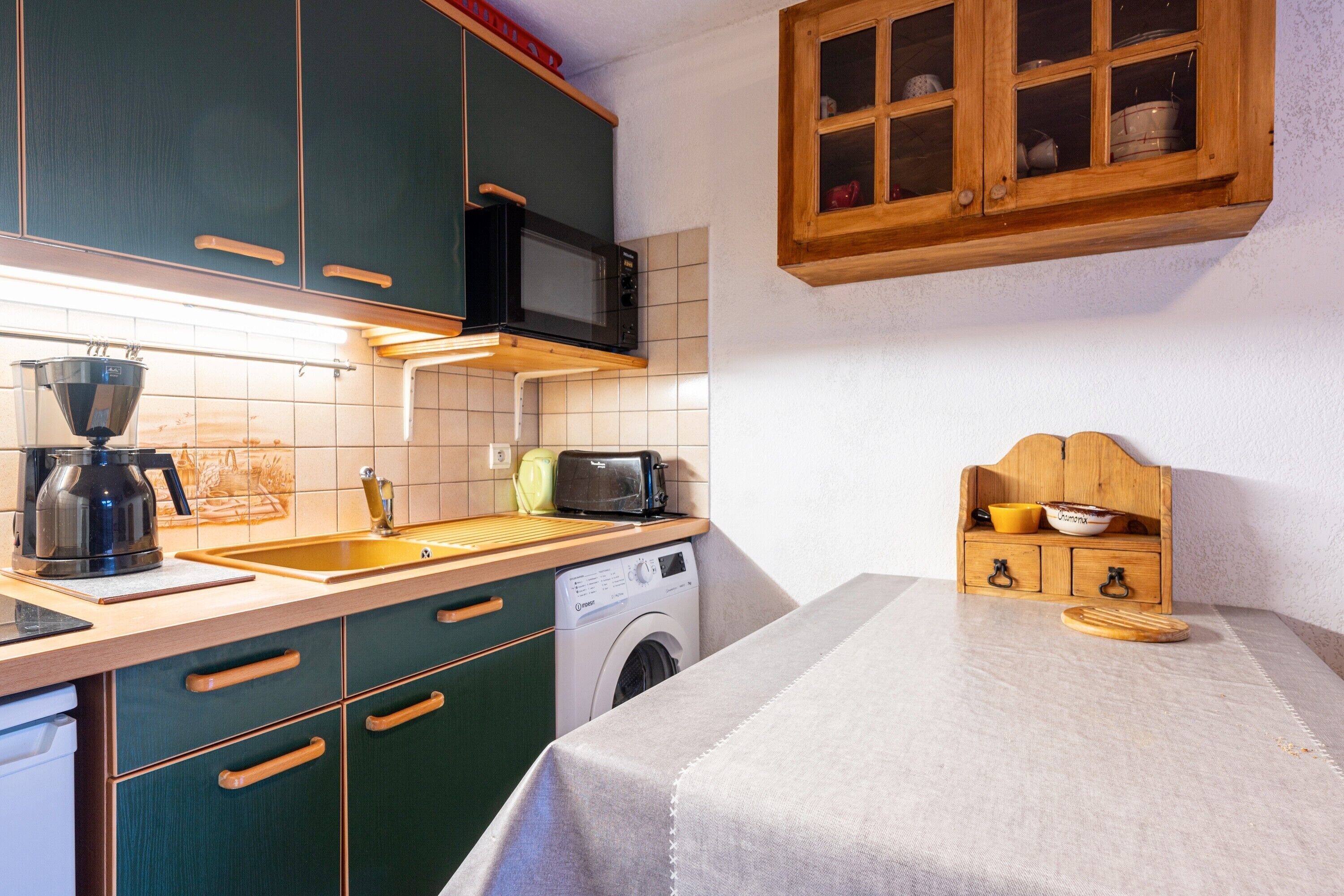 A compact kitchen with a washing machine, a microwave, and a toaster.