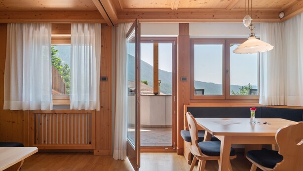 Um interior de madeira com área de refeições, um banco e vista para o exterior.