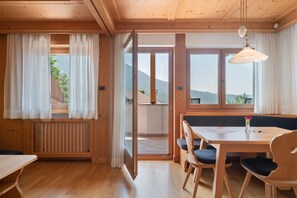 A wooden interior with a dining area, a bench, and a view of the outdoors. - Apartment 'Villa Nussbaumer B' with Mountain View, Private Terrace and Wi-Fi (Siusi allo Sciliar)