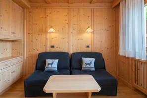 A wooden-paneled room with two sofas, a table, and wall-mounted lights. - Apartment 'Villa Nussbaumer B' with Mountain View, Private Terrace and Wi-Fi (Siusi allo Sciliar)