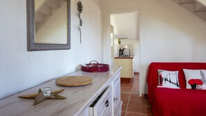 Een kamer met een houten dressoir, een rode bank, een spiegel en een trap naar een andere kamer.