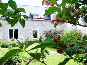 A stone house with a garden, a visible window, and a door. - Holiday Home 'Gite La Lande Cote De Granit' with Private Terrace, Private Garden and Wi-Fi (Lannion)