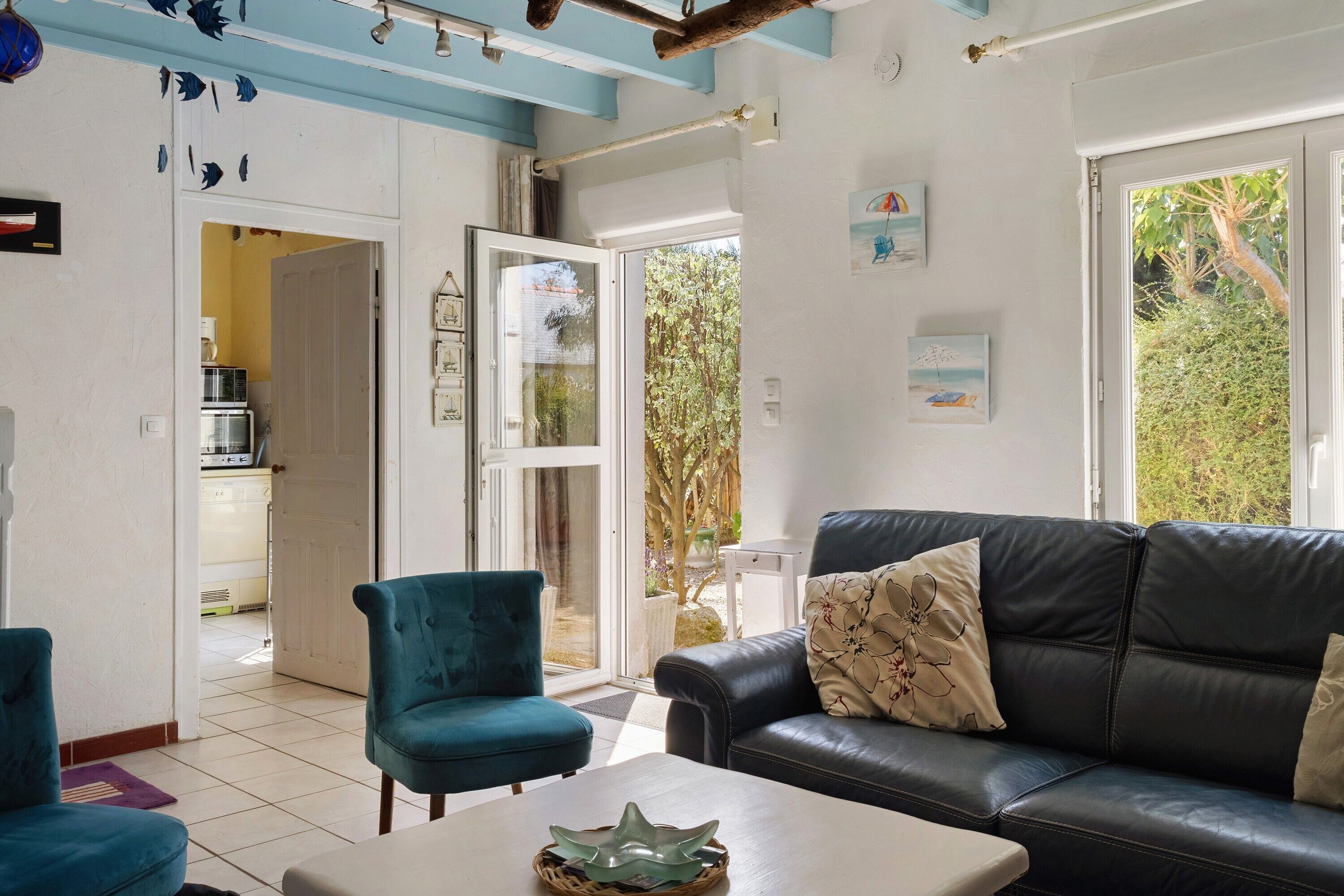 A living room with a black leather sofa, a teal armchair, and a coffee table with decorative items.