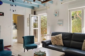 A living room with a black leather sofa, a teal armchair, and a coffee table with decorative items.