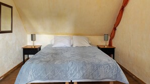 Un dormitorio con una cama, dos mesitas de noche y una lámpara a cada lado.
