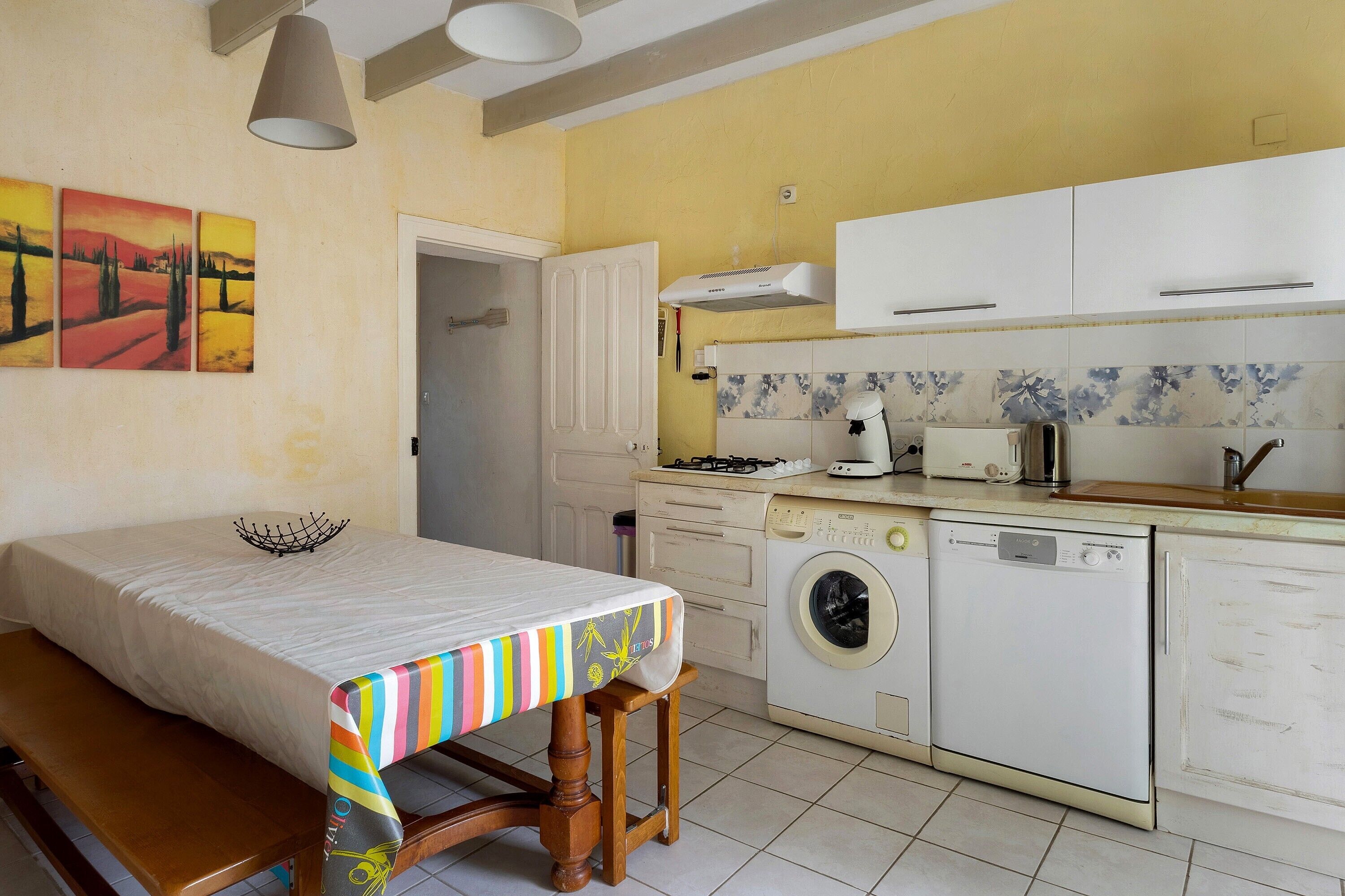 Cocina compacta con comedor, lavadora y estufa.