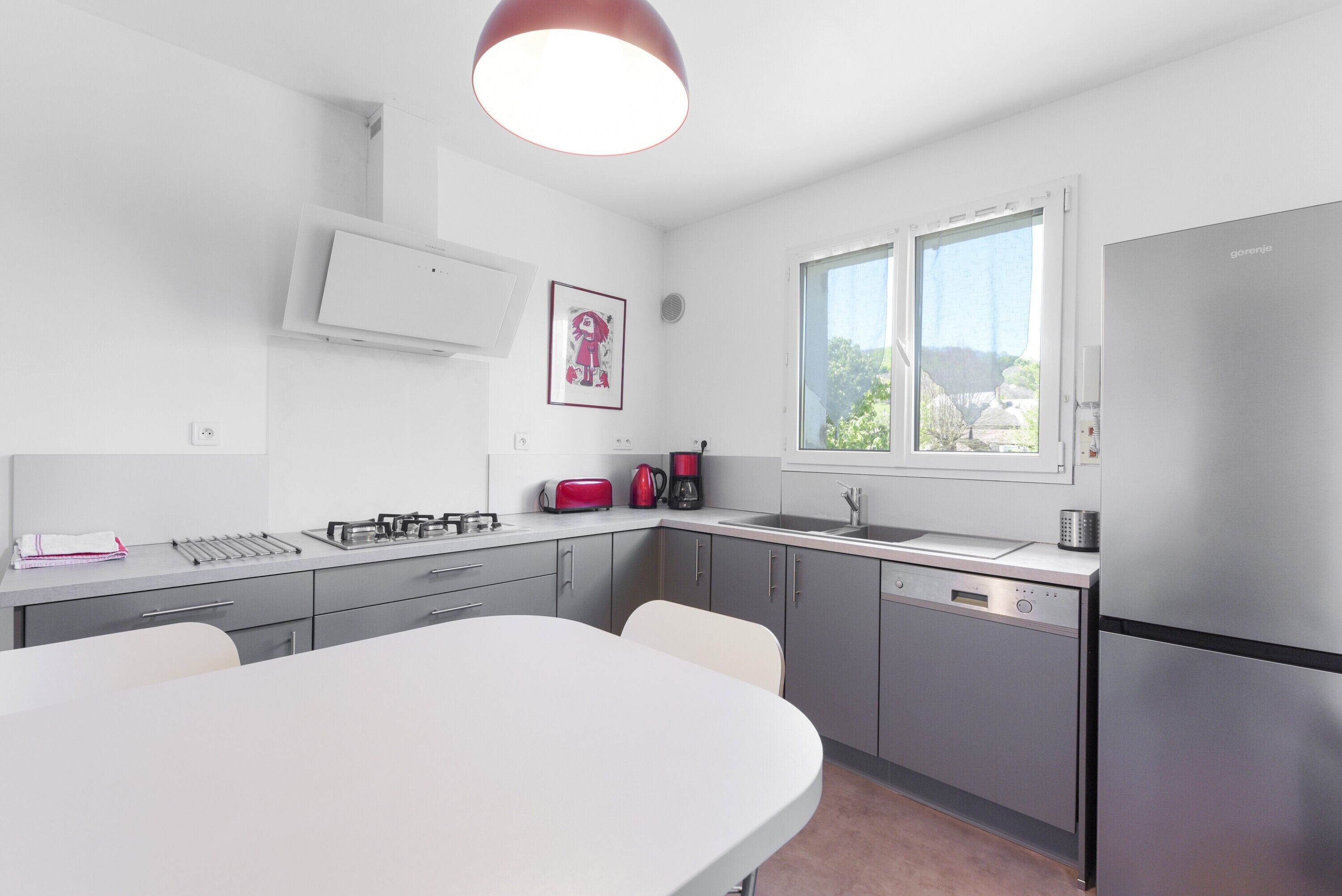 Una cucina moderna con zona pranzo, elettrodomestici in acciaio inossidabile e una finestra che lascia entrare luce naturale.