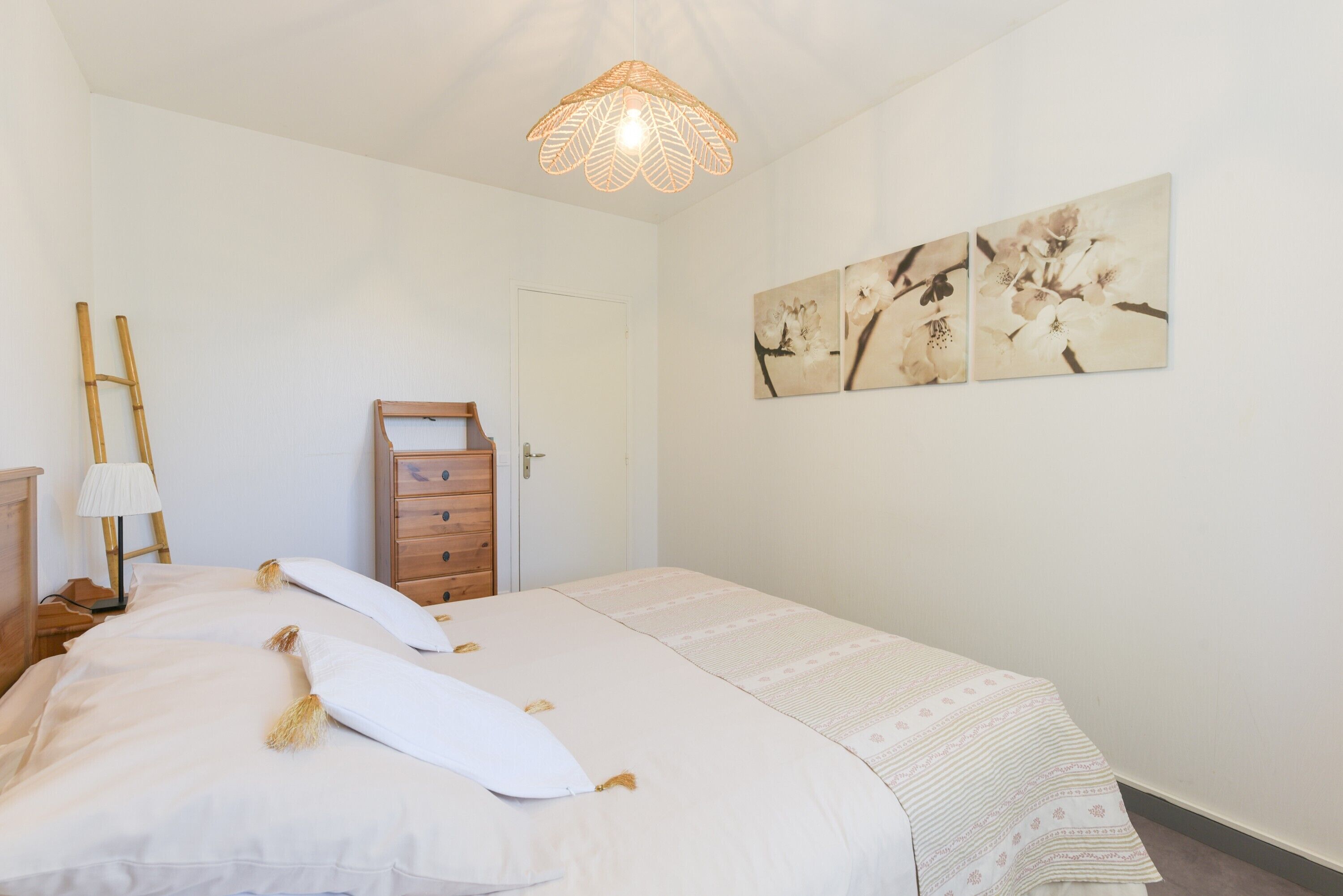 Une chambre à coucher avec un lit, une commode en bois, une porte et des œuvres d’art murales.