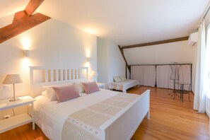 A bedroom with a bed, bedside tables, a small table, and a chair.