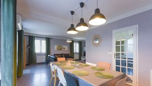 Un área de comedor con una mesa lista para cuatro, un sofá al fondo y una puerta que da a un balcón.
