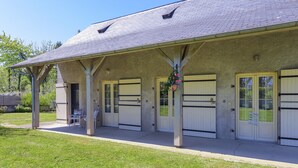 A building with a covered patio, multiple doors, and a hanging flower basket.
