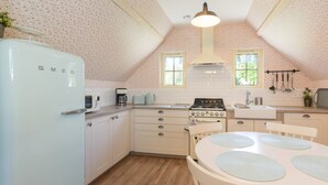 A kitchen with white cabinetry, a white refrigerator, a stove, and a dining table with placemats.