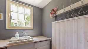 A bathroom with a window, a sink, a mirror, a towel rack, and a wooden cabinet.