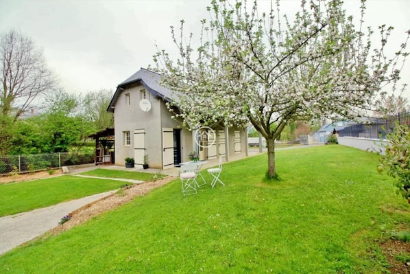 A two-story house with a sloped roof, a small porch, and a well-maintained lawn.