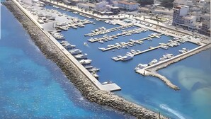 An aerial view of a marina with boats docked, a stone breakwater, and surrounding buildings. - Apartment 'Wonderful' with Sea View, Wi-Fi and Air Conditioning (Can Picafort)