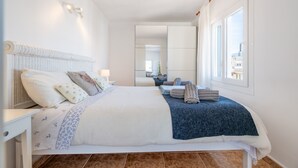 A modern hotel room with a large bed, a bedside table, a mirror, and a window with a city view. - Apartment 'Wonderful' with Sea View, Wi-Fi and Air Conditioning (Can Picafort)