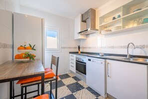 A modern kitchen with a dining table, chairs, a built-in oven, and a dishwasher. - Apartment 'Fantastic' with Private Terrace, Wi-Fi and Air Conditioning (Can Picafort)