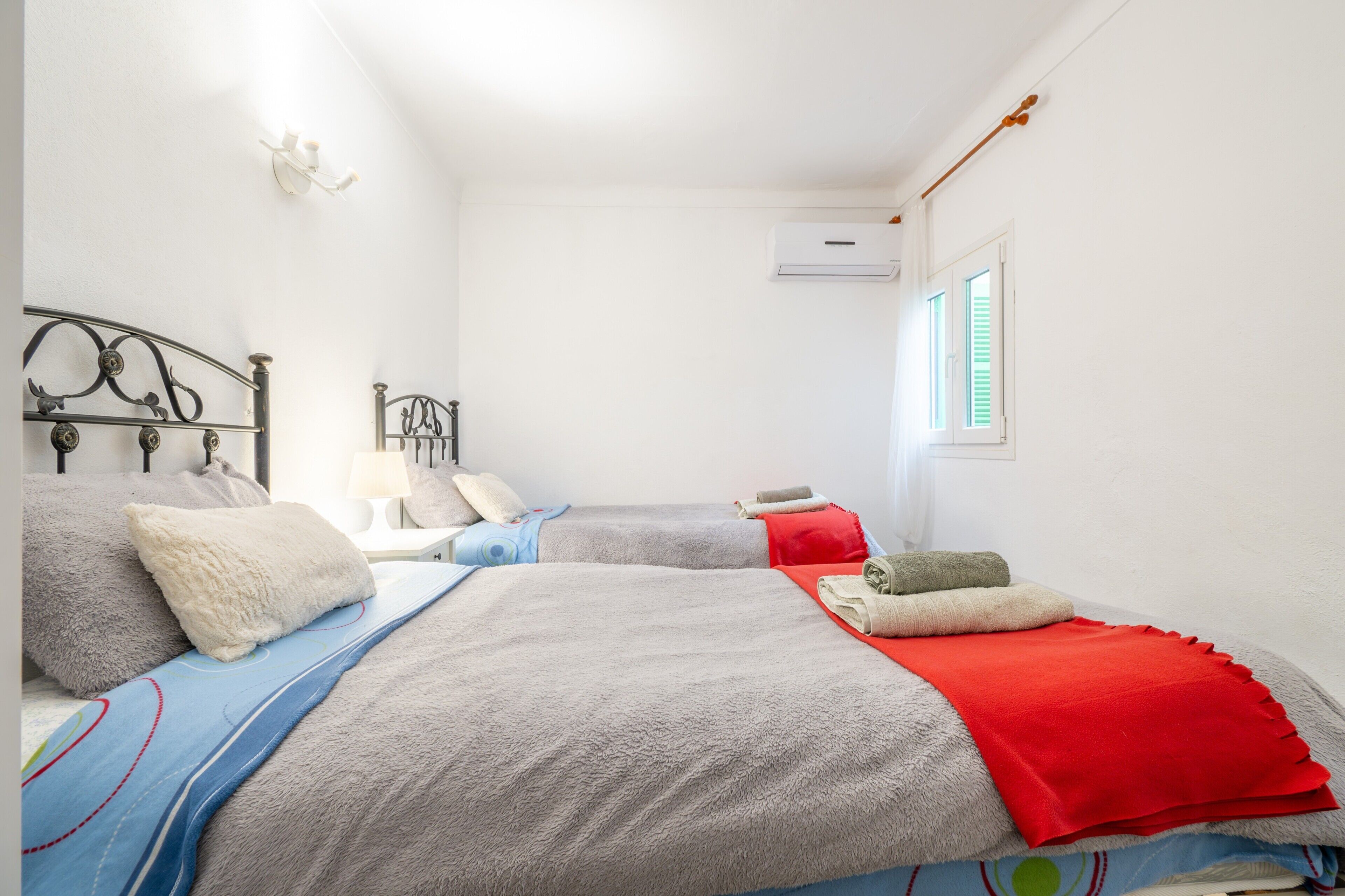 Un dormitorio con dos camas, una mesita de noche, una lámpara y un equipo de aire acondicionado.