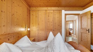 Una habitación tipo cabaña de madera con cama, almohadas, mesita de noche y una lámpara fijada a la pared.