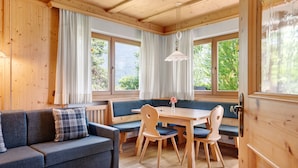 Una habitación acogedora con un sofá, una mesa de comedor de madera y un banco.