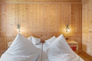 Quarto com painéis de madeira, uma cama, duas mesas de cabeceira e luminárias fixadas na parede.