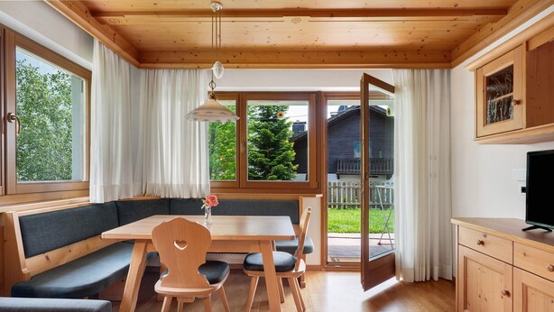 Un interior de madera con una mesa de comedor, bancos y un televisor.