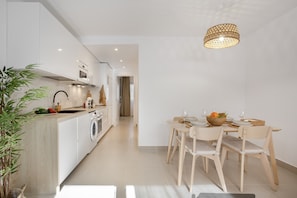 Una cocina moderna con comedor, muebles de madera y una lámpara colgante.