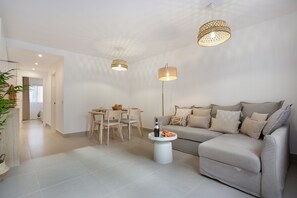 Una sala moderna con sofá, mesa de comedor, sillas e iluminación colgante.