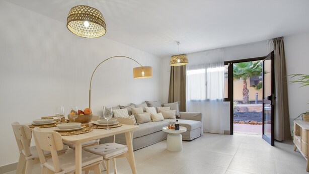 A modern living room with a dining area, a sofa, and a view of the outdoors.