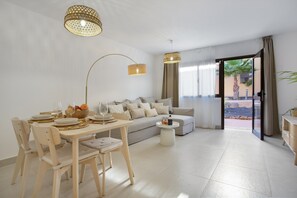 Una sala de estar moderna con comedor, sofá y vistas al exterior.