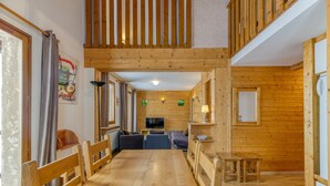 A wooden interior with a dining area, seating, and a television.