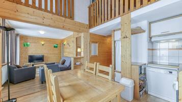 Un intérieur en bois comprenant une table à manger, des canapés, un téléviseur et un coin cuisine.