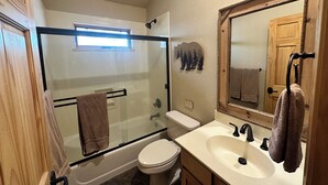A bathroom with a glass-enclosed shower, a toilet, a sink, and a mirror.